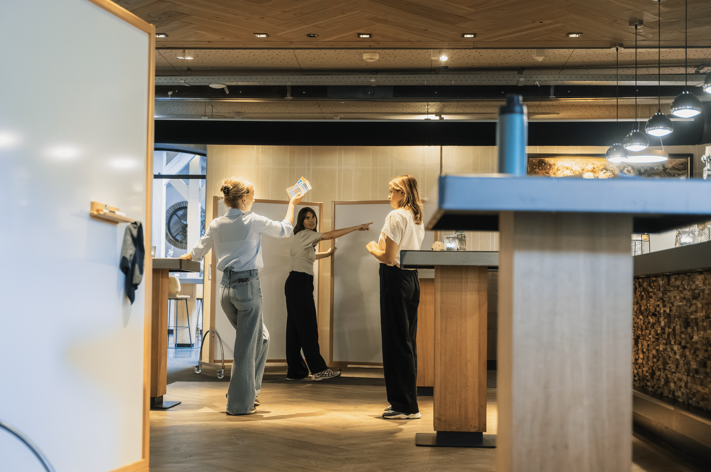 Drie deelnemers werken samen bij whiteboards